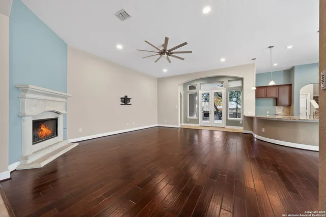 a view of an empty room and kitchen with fireplace wooden floor