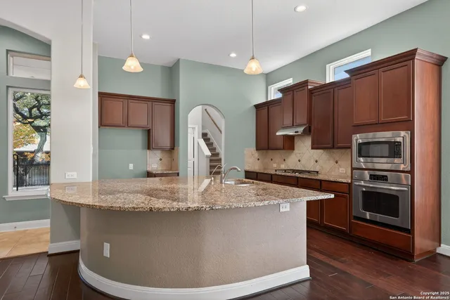 a kitchen with kitchen island granite countertop a sink stove and refrigerator