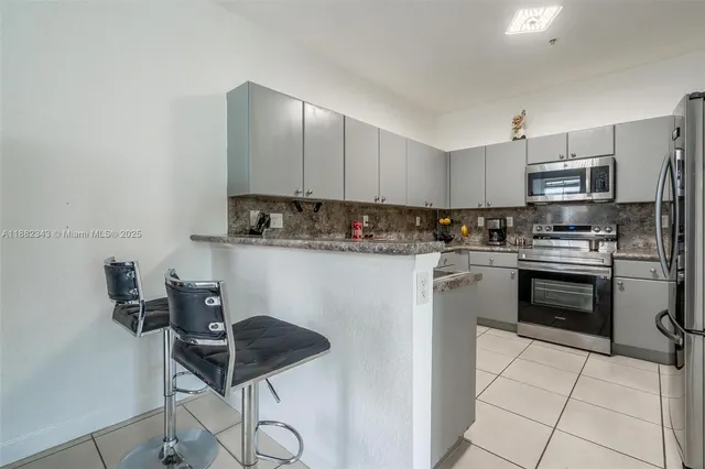 a kitchen with stainless steel appliances granite countertop a sink a stove a refrigerator cabinets and chairs