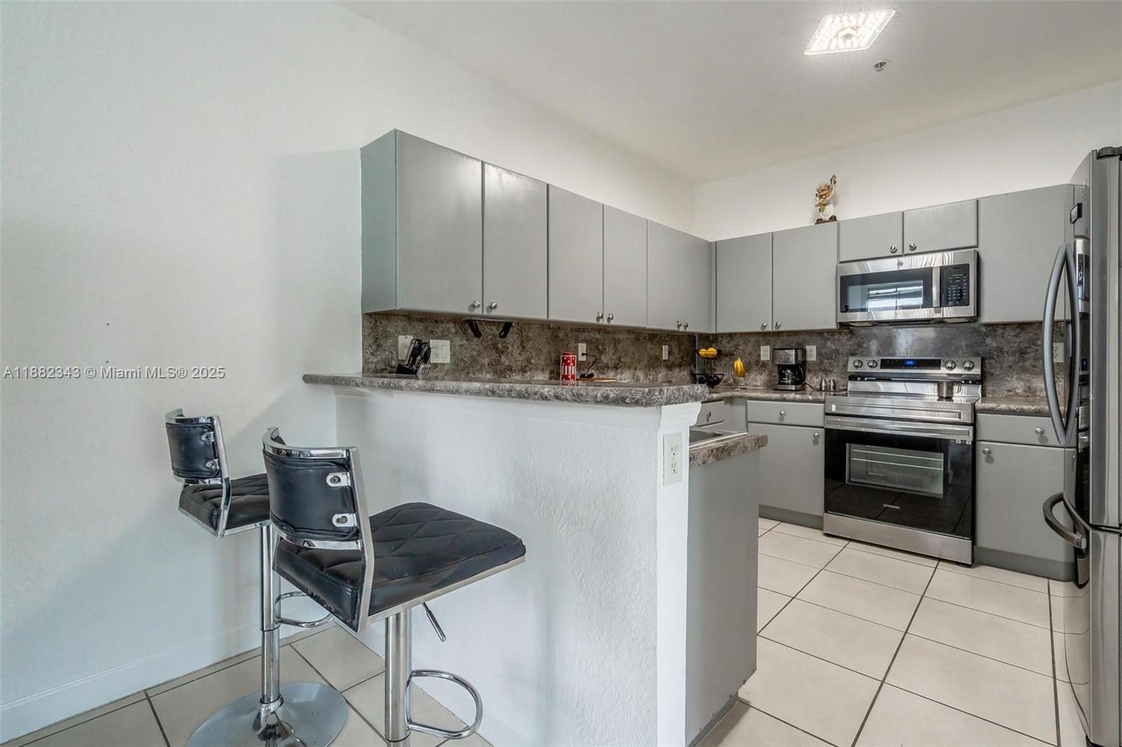 4455 Southwest 160th Avenue, Unit 205 Miramar, FL 33027 - Photo 13 of 44 a kitchen with stainless steel appliances granite countertop a sink a stove a refrigerator cabinets and chairs