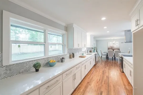 a kitchen with granite countertop lots of counter top space a sink appliances and a large window