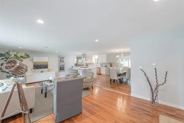 a living room with couches and kitchen view with wooden floor