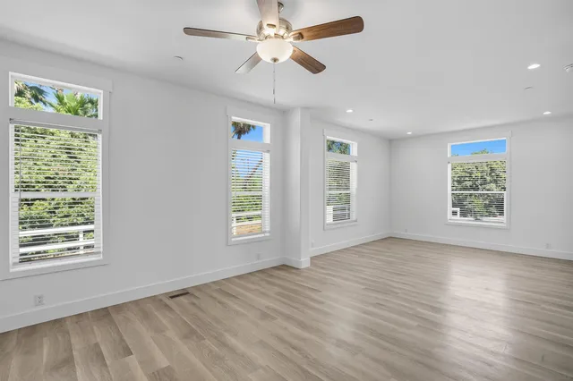 a view of an empty room with a window and wooden floor