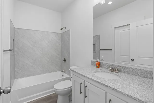 a bathroom with a granite countertop sink a toilet and shower