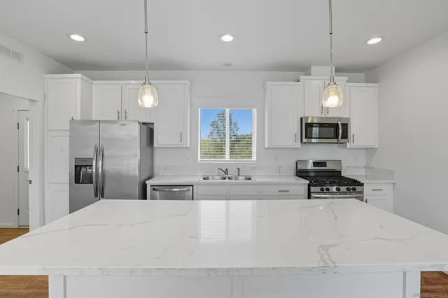 a large white kitchen with a refrigerator a stove a sink and a window