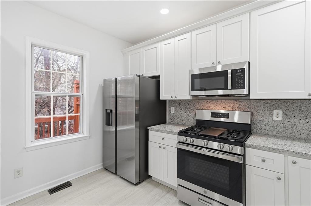 3349 Lathenview Court Alpharetta, GA 30004 - Photo 5 of 48 a kitchen with stainless steel appliances white cabinets a stove a microwave and a window