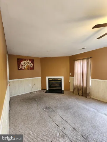 a view of an empty room with a fireplace and window