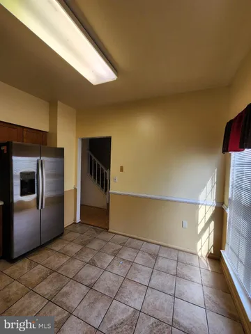 a view of a refrigerator in kitchen and an empty room