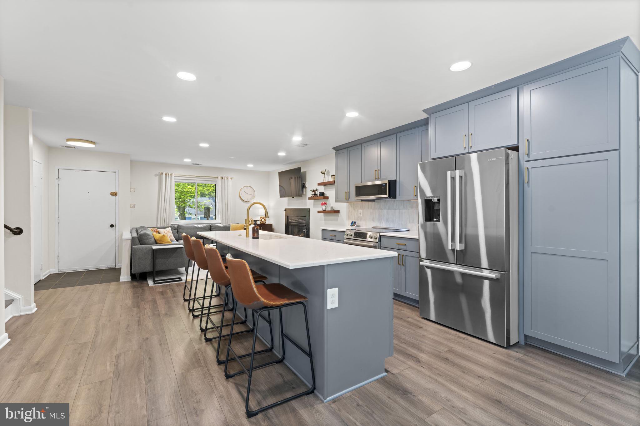 11308 Gatesborough Lane Reston, VA 20191 - Photo 11 of 58 a kitchen with kitchen island a stove a refrigerator and a dining table with wooden floor
