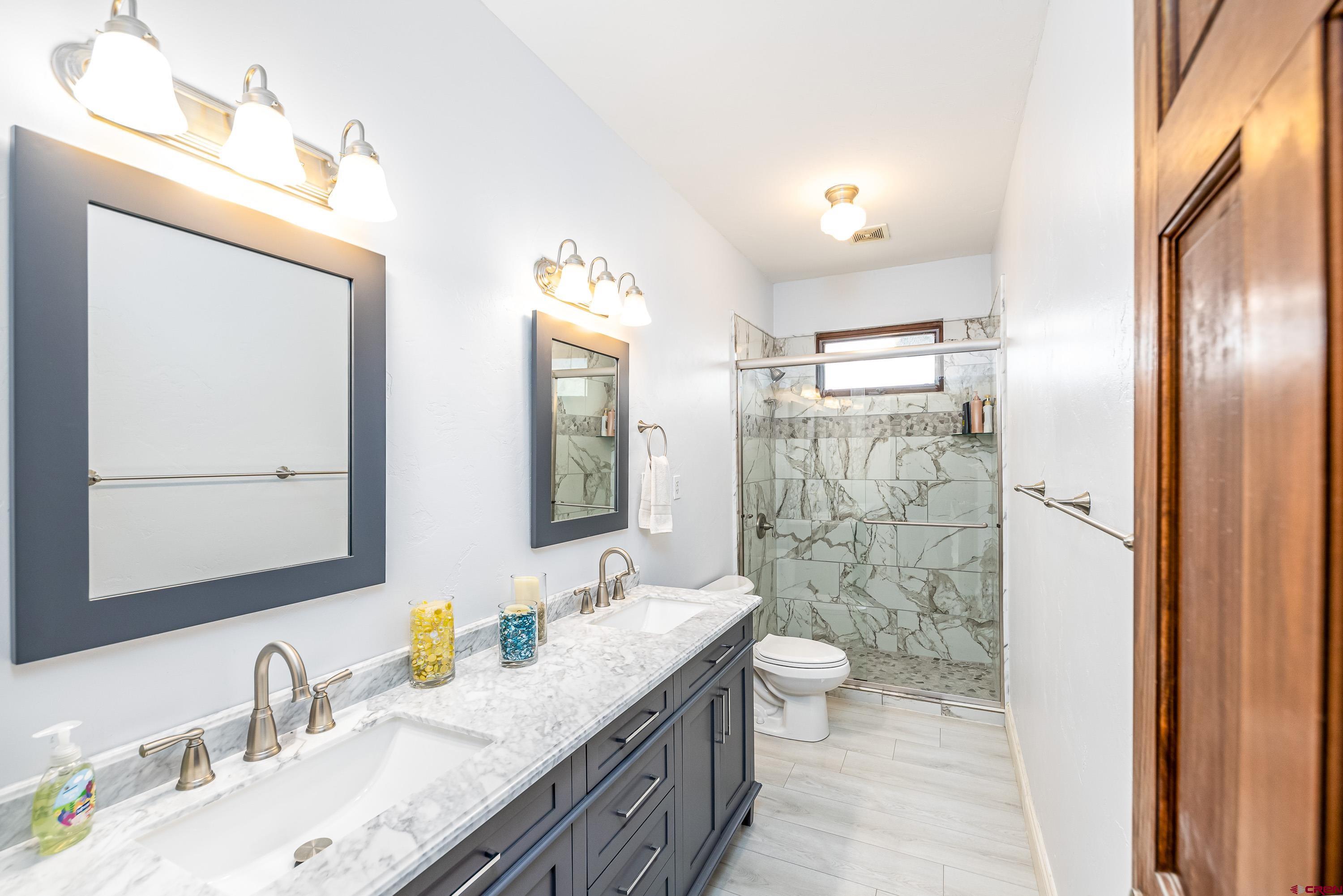 69392 Racine Road Montrose, CO 81401 - Photo 15 of 32 a bathroom with a granite countertop double vanity sink mirror and shower