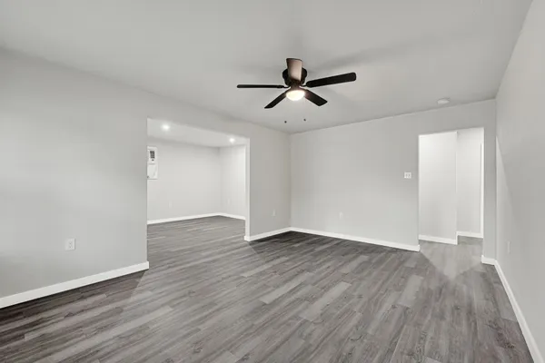 a view of empty room with wooden floor and ceiling fan