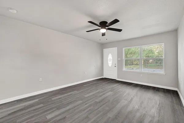 a view of an empty room with wooden floor and a window