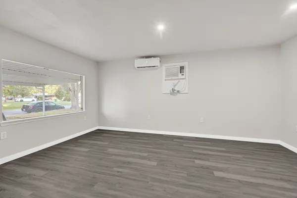 a view of an empty room with wooden floor and a window