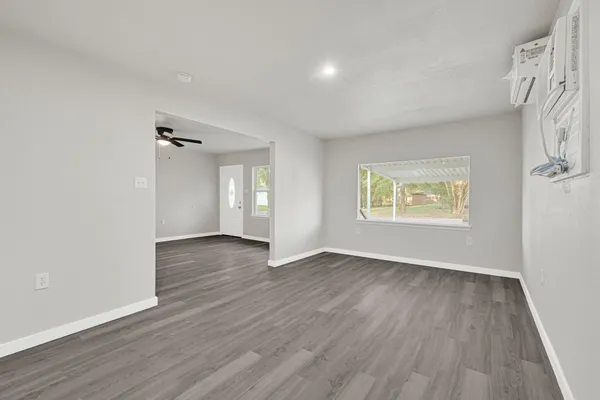 an empty room with wooden floor and windows