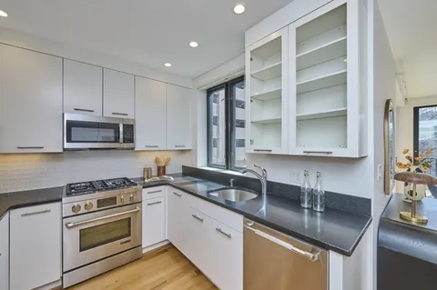 a kitchen with granite countertop a sink stainless steel appliances and cabinets