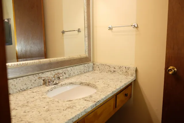 a bathroom with a granite countertop sink and a mirror