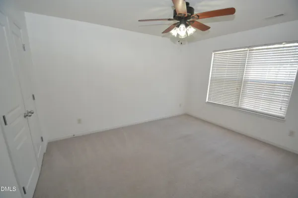 an empty room with a window and a ceiling fan