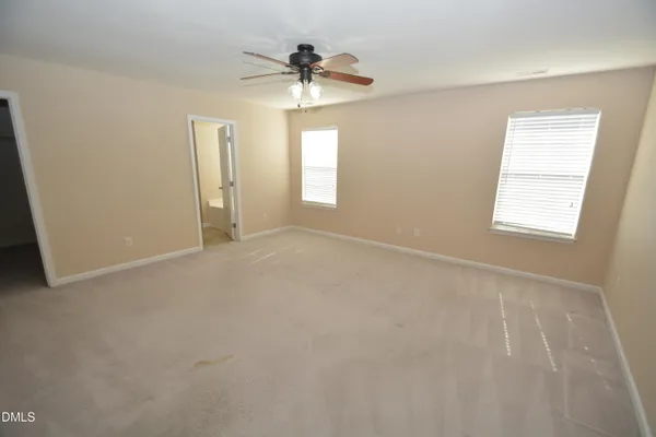 an empty room with windows and chandelier fan