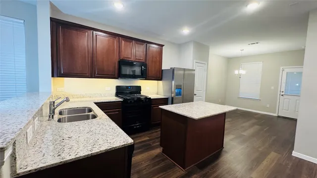 a kitchen with kitchen island granite countertop a sink a stove and refrigerator