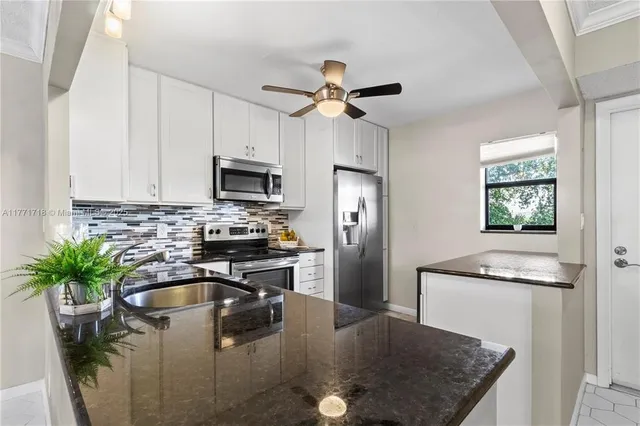 a kitchen with stainless steel appliances granite countertop a sink a stove a refrigerator a washer dryer and cabinets