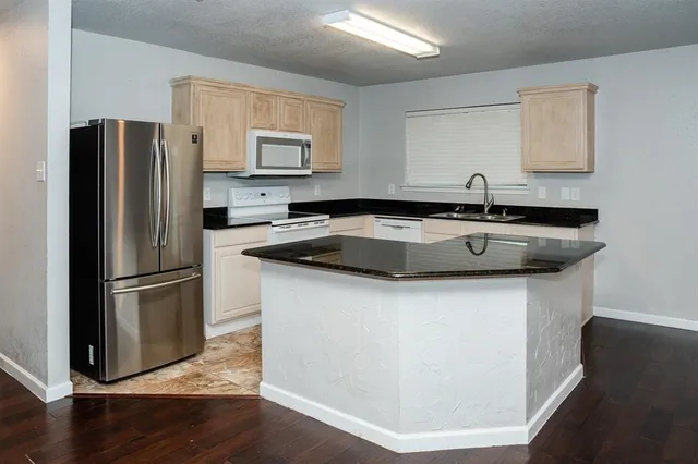 an open kitchen with wooden floor and stainless steel appliances