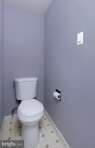 a white toilet sitting next to a white wall
