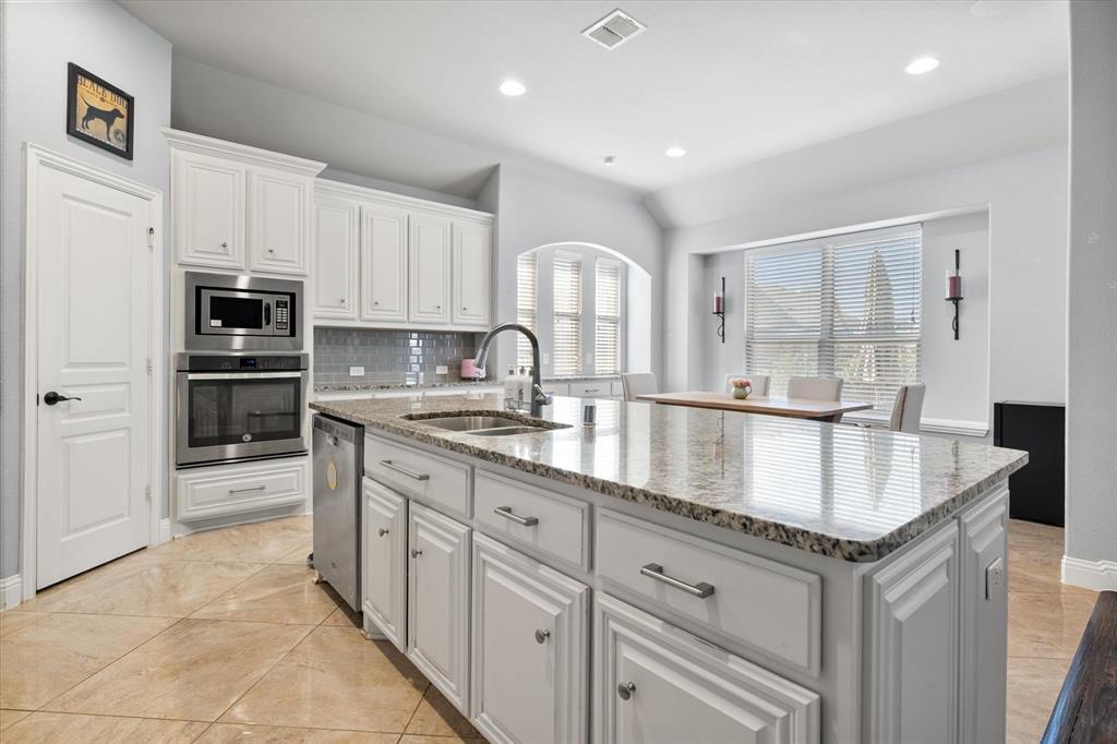 7235 Neblina Drive Grand Prairie, TX 75054 - Photo 12 of 32 a kitchen with granite countertop a sink stove and cabinets