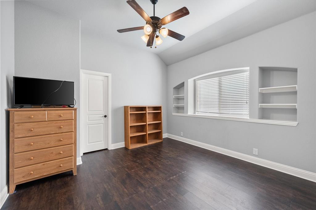 7235 Neblina Drive Grand Prairie, TX 75054 - Photo 21 of 32 a view of an empty room with a flat screen tv wooden floor and a ceiling fan