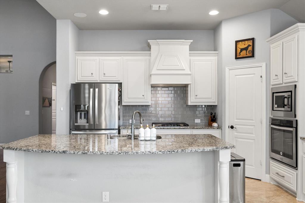7235 Neblina Drive Grand Prairie, TX 75054 - Photo 9 of 32 a kitchen with stainless steel appliances granite countertop a sink and a refrigerator