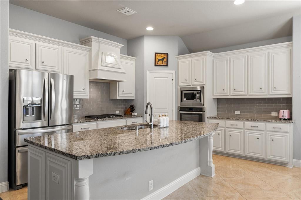 7235 Neblina Drive Grand Prairie, TX 75054 - Photo 10 of 32 a kitchen with stainless steel appliances granite countertop a sink refrigerator and cabinets