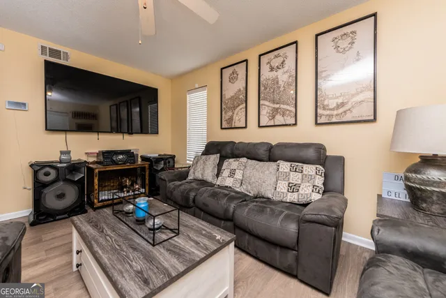 a living room with furniture a flat screen tv and kitchen view
