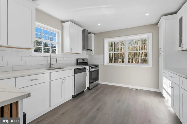 a kitchen with granite countertop white cabinets and wooden floor
