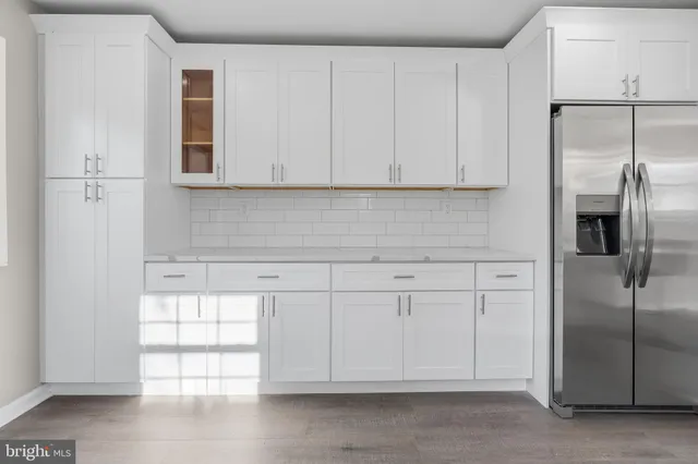 a kitchen with white cabinets and refrigerator