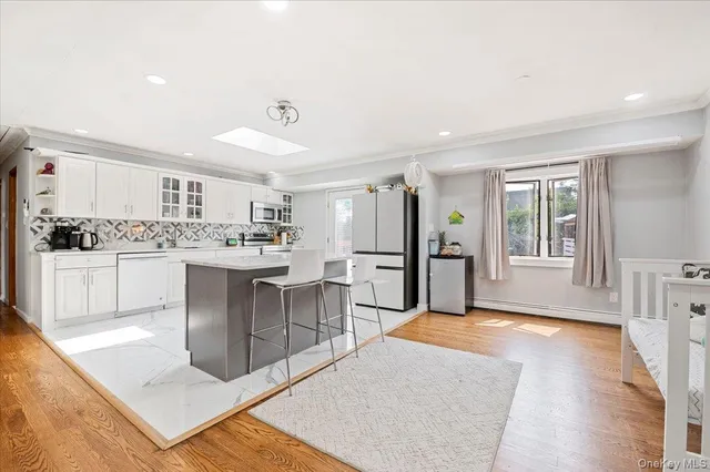 a living room with stainless steel appliances kitchen island granite countertop a sink a stove a refrigerator cabinets and a dining table