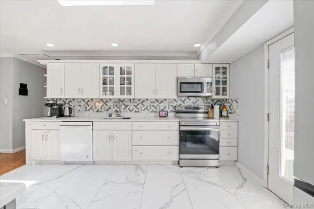 a kitchen with granite countertop white cabinets and stainless steel appliances