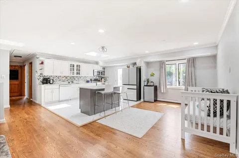 a large white kitchen with a stove a sink a couch and a dining table with wooden floor