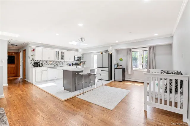 a large white kitchen with a stove a sink a couch and a dining table with wooden floor