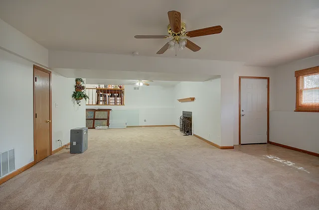 a view of an empty room and chandelier fan