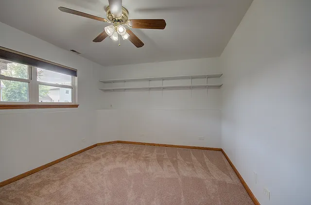 an empty room with closet and a chandelier fan
