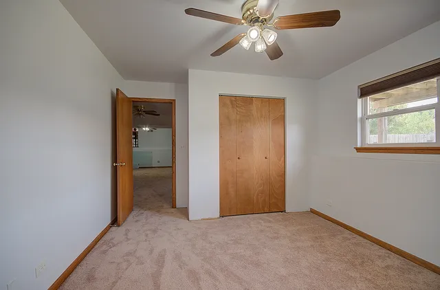 an empty room with a window and a fan