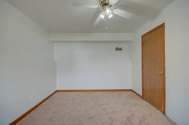 an empty room with windows and ceiling fan