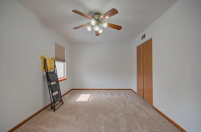 an empty room with windows and fan