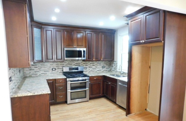 Undisclosed Address Chicago, IL 60630 - Photo 5 of 16 a kitchen with stainless steel appliances granite countertop wooden cabinets and a stove top oven