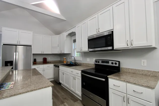 a kitchen with stainless steel appliances granite countertop a sink a stove a microwave and cabinets