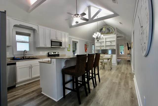 a kitchen with stainless steel appliances granite countertop a stove a sink dishwasher a dining table and chairs with wooden floor