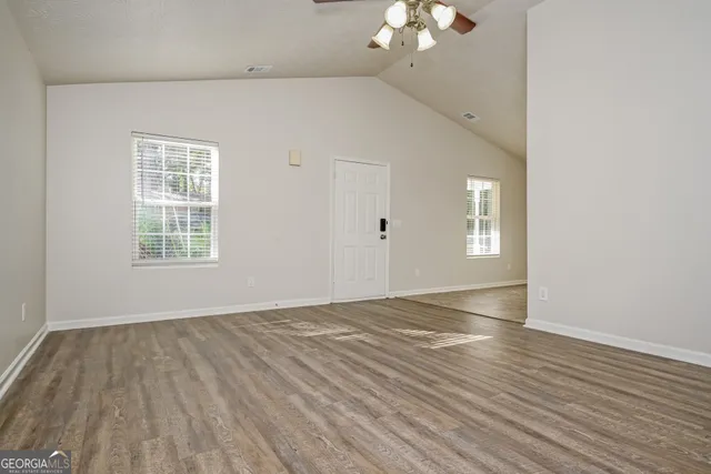 a view of an empty room with wooden floor and a window