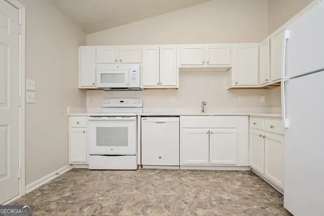 a kitchen with white cabinets and white appliances