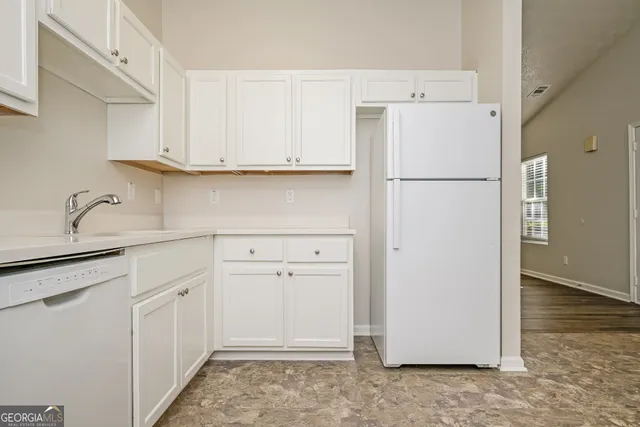 a kitchen with white cabinets and refrigerator