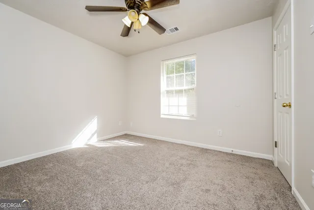an empty room with a chandelier fan and windows