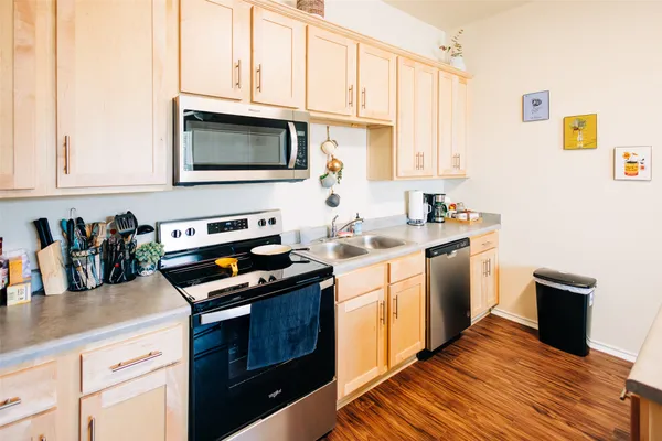 a kitchen with stainless steel appliances white cabinets sink and wooden floor